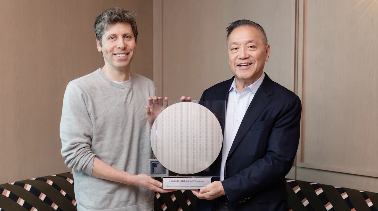 The CEOs of OpenAI and Broadcom stand flanking a circular semiconductor wafer.