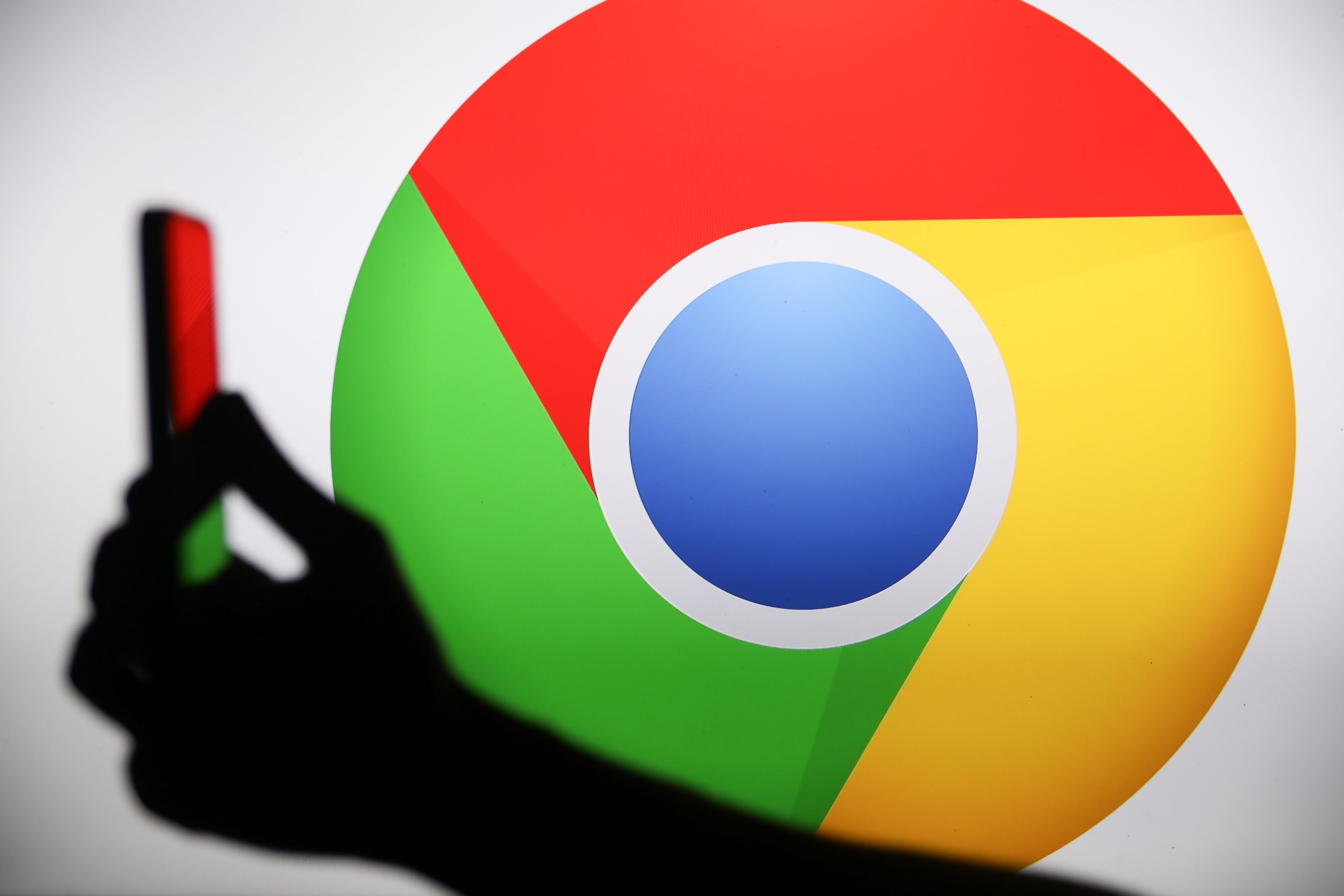 The Chrome logo displays on a screen with a person holding a phone.