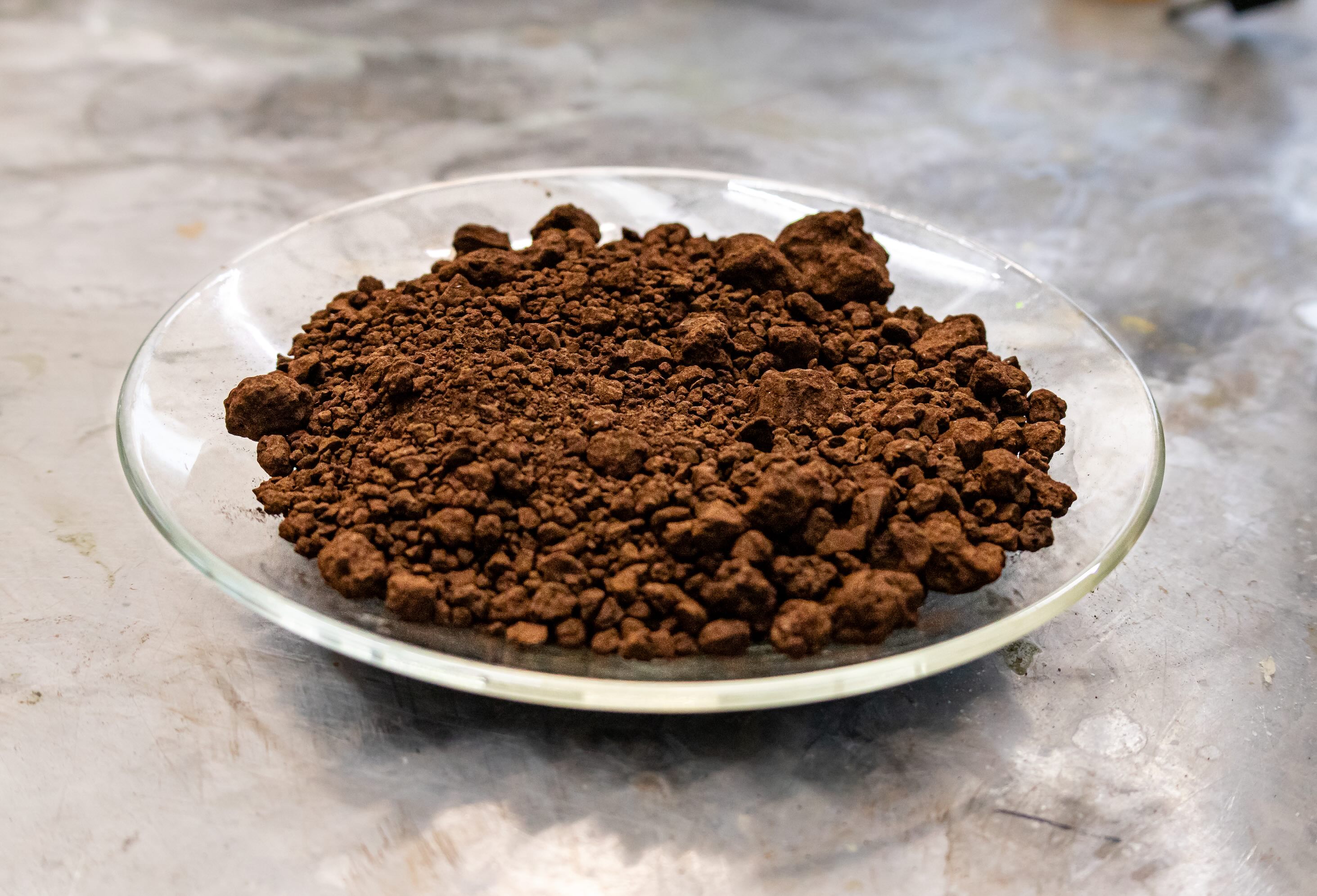 A plate of red mud sits on a lab workbench.